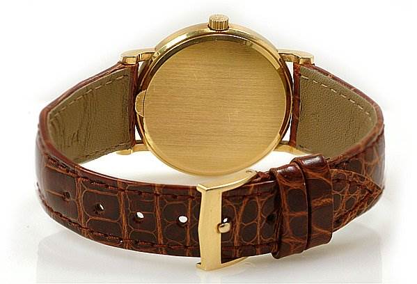 This image shows the rear view of a Patek Philippe Calatrava 3802/200 Men's Yellow Gold White Dial 3802/200 Men's Yellow Gold White Dial watch with a gold case and a brown leather strap.