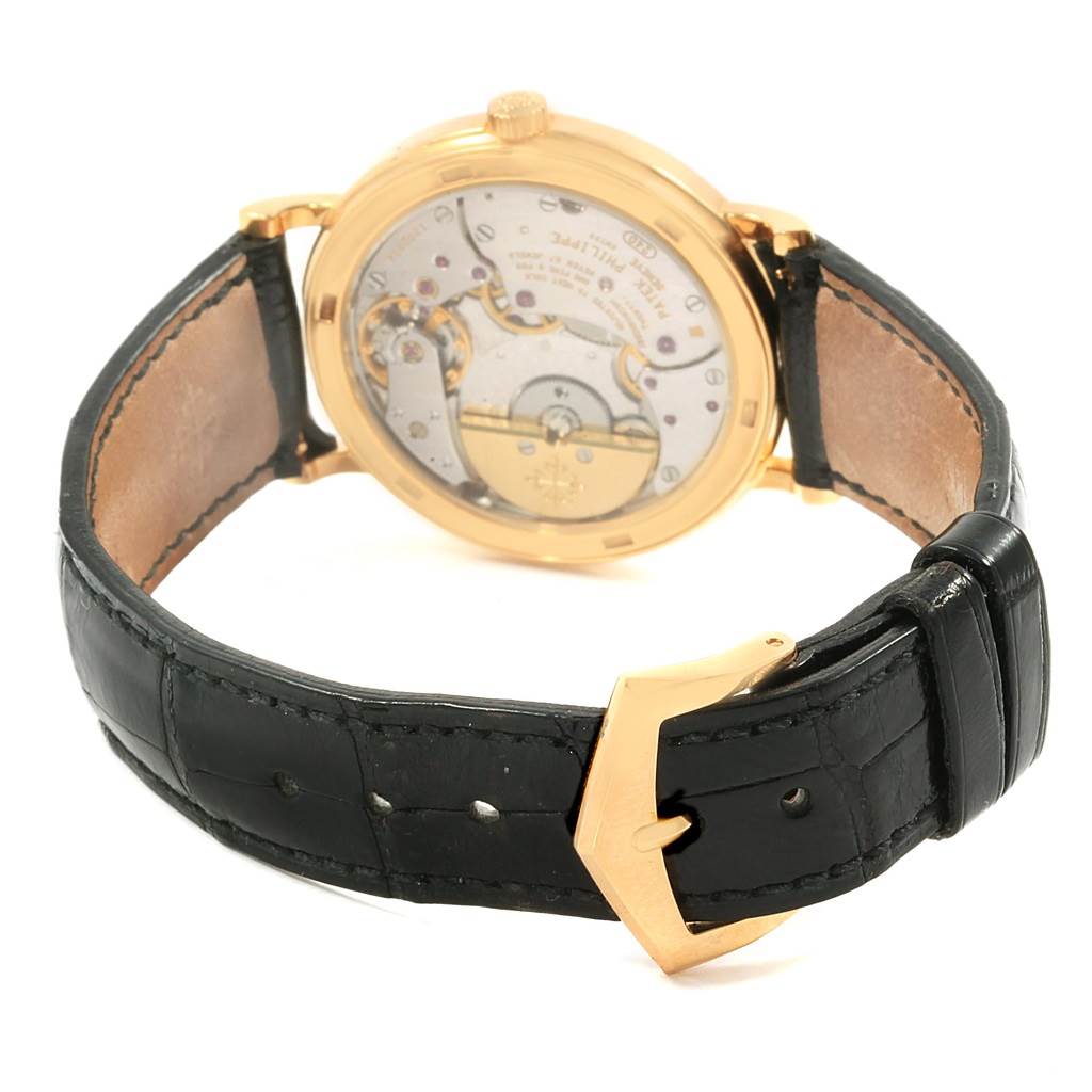 The image shows the backside view of a Patek Philippe Calatrava 5120J Men's Yellow Gold White Dial 5120J Men's Yellow Gold White Dial watch, highlighting its movement and black leather strap.