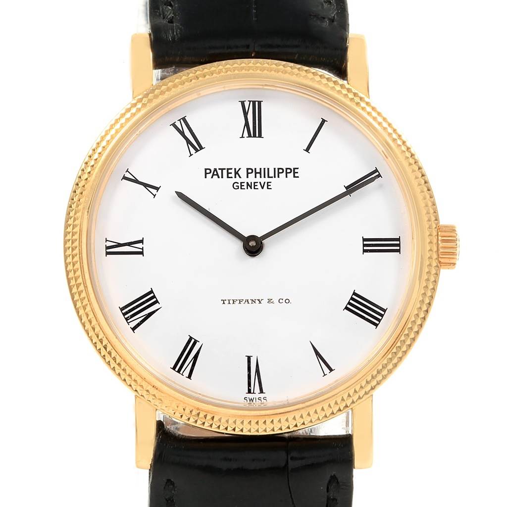 The image shows a front view of the Patek Philippe Calatrava 5120J Men's Yellow Gold White Dial 5120J Men's Yellow Gold White Dial watch, highlighting its dial, roman numerals, and black leather strap.