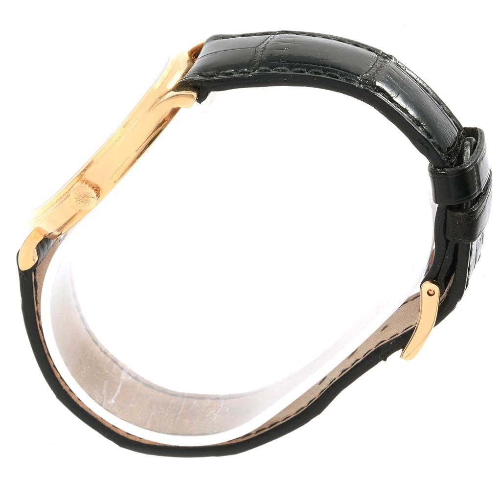 The image shows a side view of a Patek Philippe Calatrava 5120J Men's Yellow Gold White Dial 5120J Men's Yellow Gold White Dial watch, highlighting its black leather strap and gold clasp.