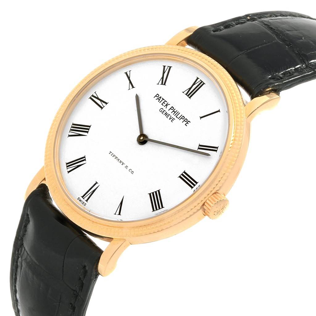 This image shows a Patek Philippe Calatrava 5120J Men's Yellow Gold White Dial 5120J Men's Yellow Gold White Dial watch at an oblique angle, highlighting its dial, crown, and leather strap.