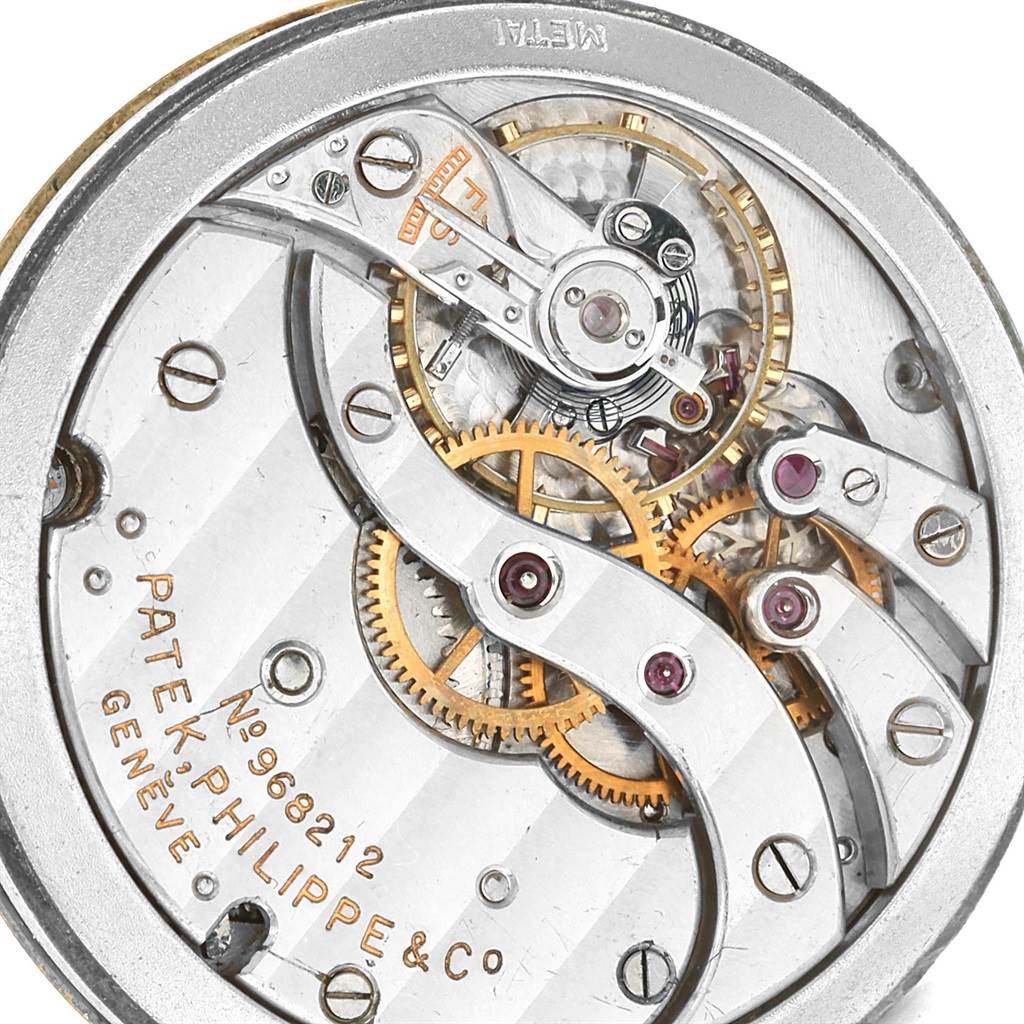 This image shows the intricate inner mechanism of a Vintage Patek Philippe watch, highlighting gears and engraved details.