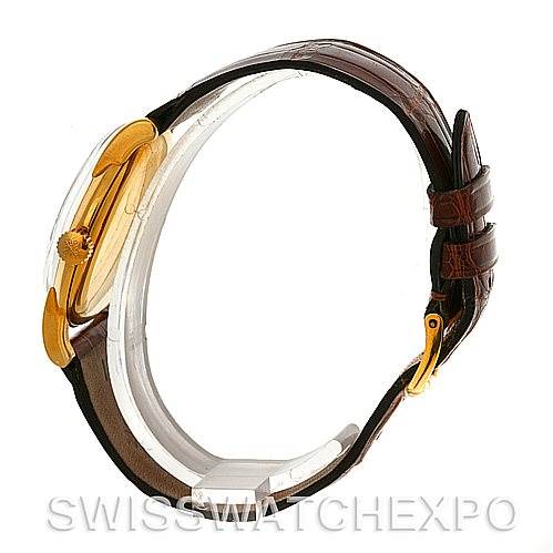 This side view of a Vintage Patek Philippe watch displays the golden case, crown, and brown leather strap with a buckle.