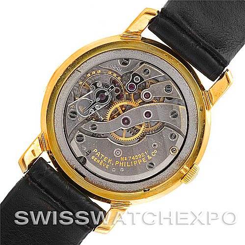 The image shows the back view of a Vintage Patek Philippe watch, revealing its intricate mechanical movement and inner components.