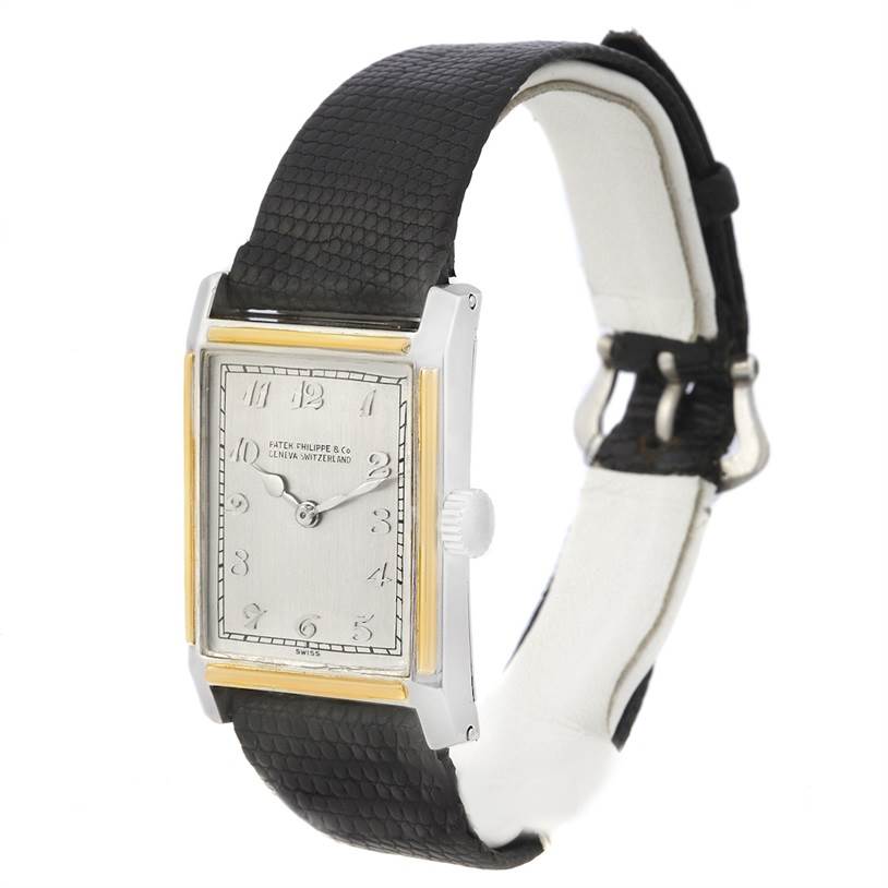The image shows a side-angled view of a Patek Philippe Vintage Men
s Platinum Silver Dial Men
s Platinum Silver Dial watch with a rectangular dial, gold accents, and a black leather strap.