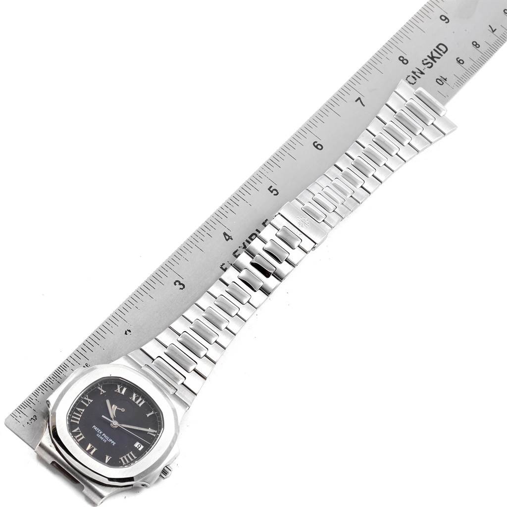 The image shows a Patek Philippe Nautilus 3710/1A Men's Stainless Steel Black Dial 3710/1A Men's Stainless Steel Black Dial watch laid flat next to a ruler, highlighting its bracelet and dial from a top-down angle.