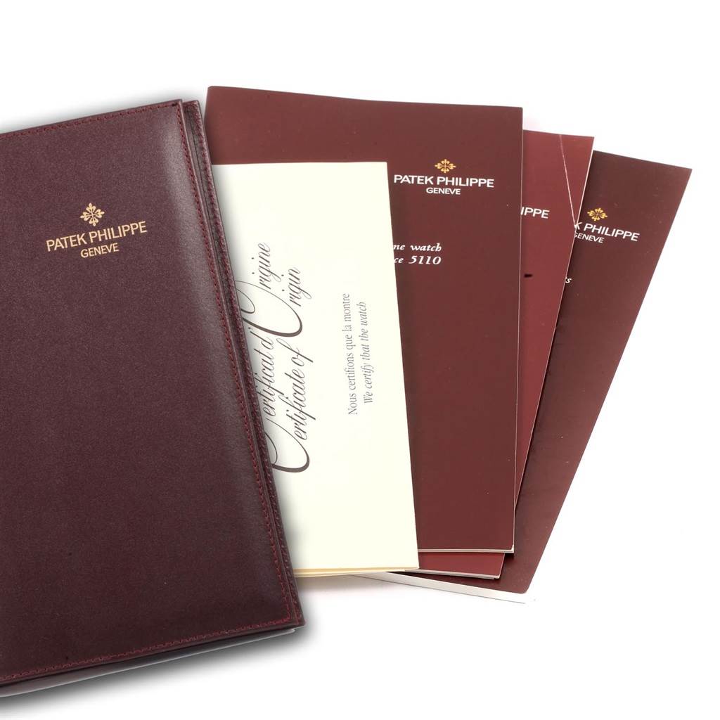 The image shows Patek Philippe Complications 5110J Men
s Yellow Gold Silver Dial 5110J Men
s Yellow Gold Silver Dial model booklets and a Certificate of Origin from an angled top view.