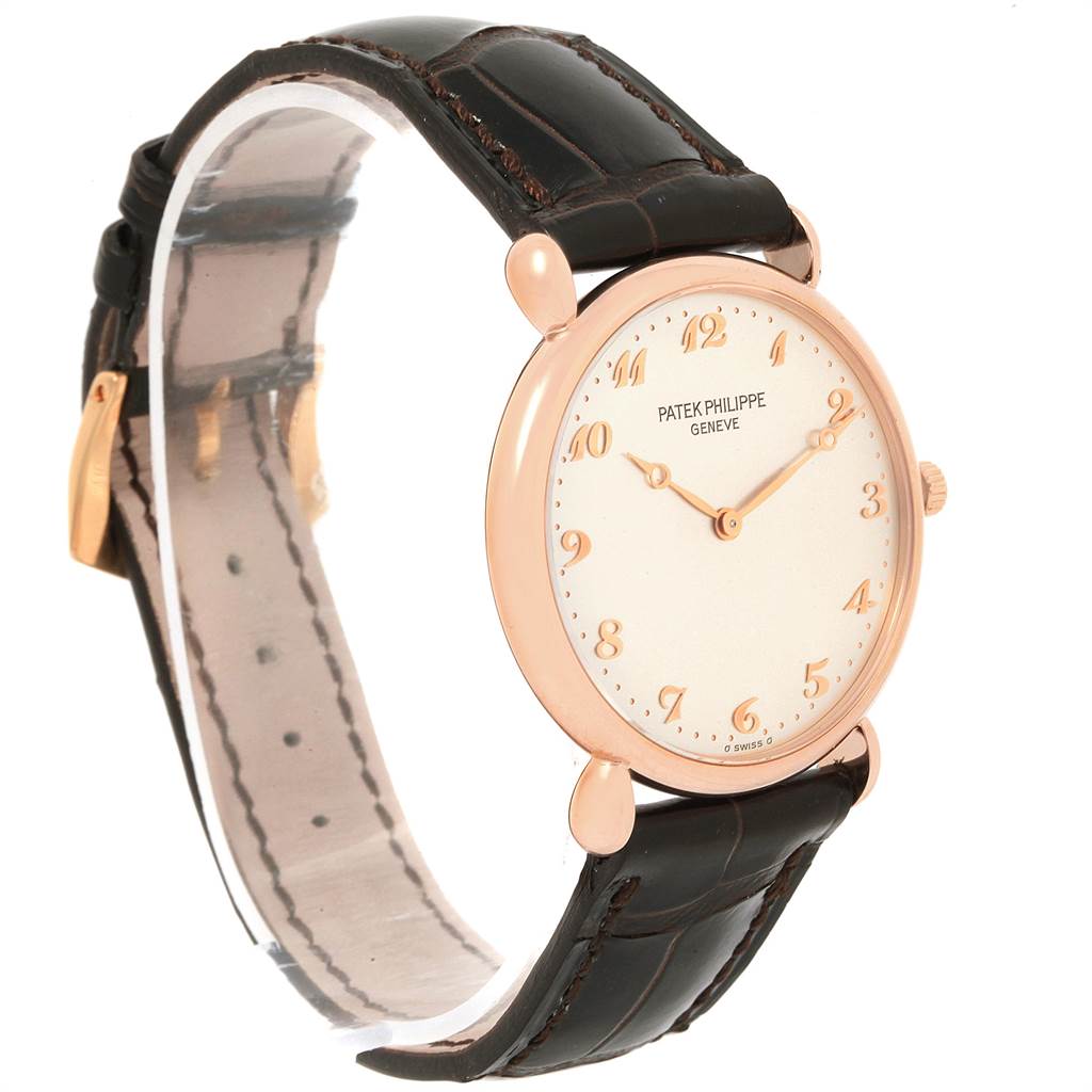 The image shows a side angle view of a vintage Patek Philippe watch with a brown leather strap and round gold case.