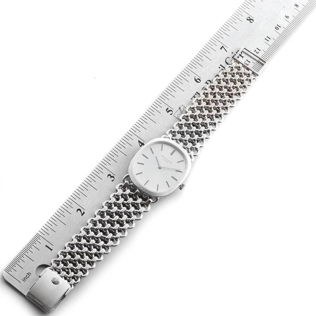 The image shows a top view of a Patek Philippe Golden Ellipse 3577 Men's White Gold Silver Dial 3577 Men's White Gold Silver Dial watch alongside a ruler, highlighting its metal bracelet and face.
