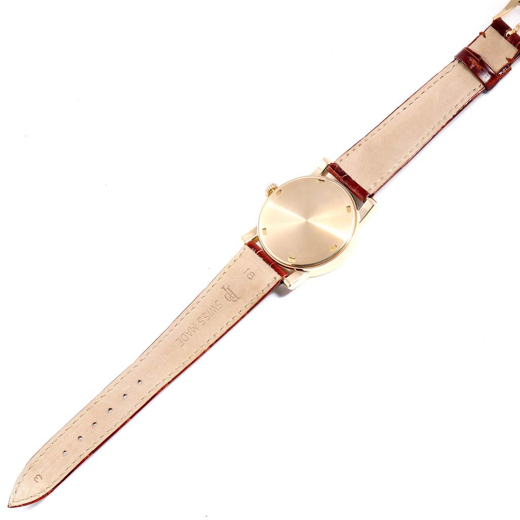 This image shows a Patek Philippe Calatrava 5012 Men's Yellow Gold Beige Dial 5012 Men's Yellow Gold Beige Dial watch from a top-down angle, including its gold case and leather strap.