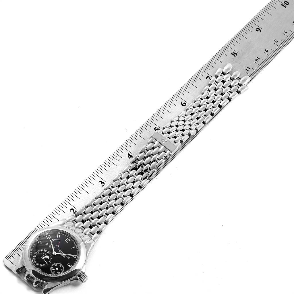 The image shows a Patek Philippe Neptune 5085A/1A-001 Men's Stainless Steel Black Dial 5085A/1A-001 Men's Stainless Steel Black Dial model watch with its face and metal bracelet fully extended alongside a ruler.