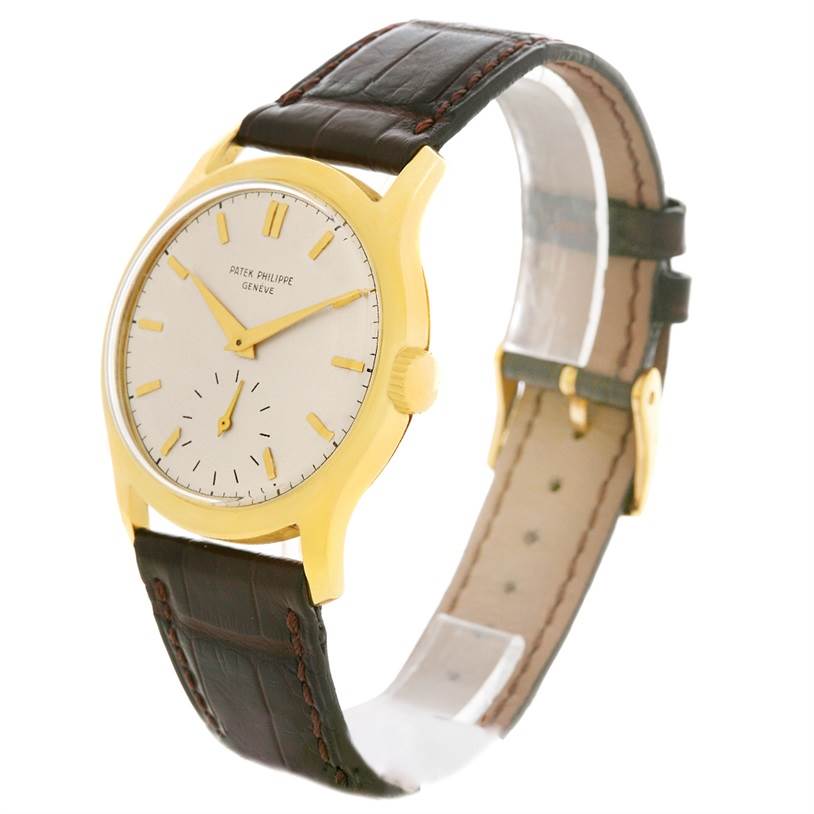 This image shows a side-angle view of a Vintage Patek Philippe watch highlighting its gold case, white dial, and brown leather strap.