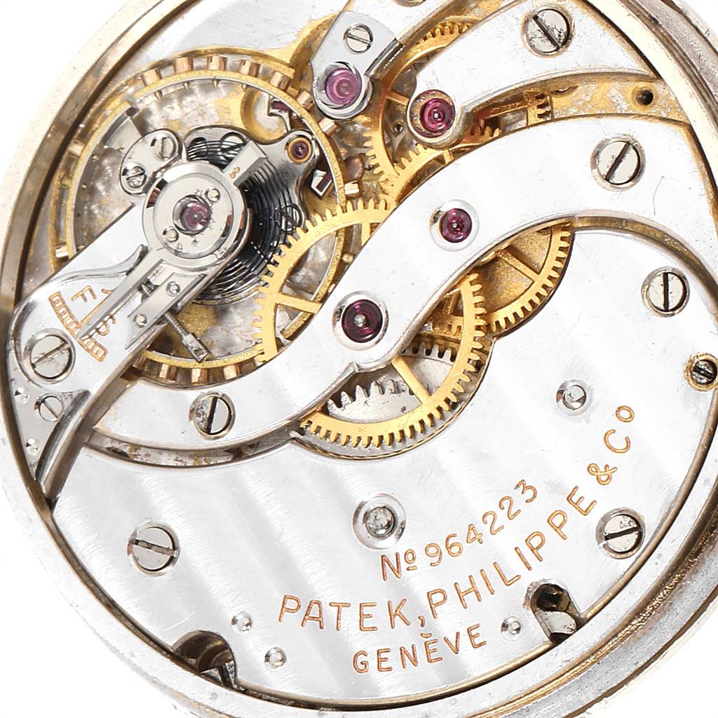 The image shows an angled close-up of the intricate mechanics inside a Vintage Patek Philippe watch, highlighting gears and serial number.