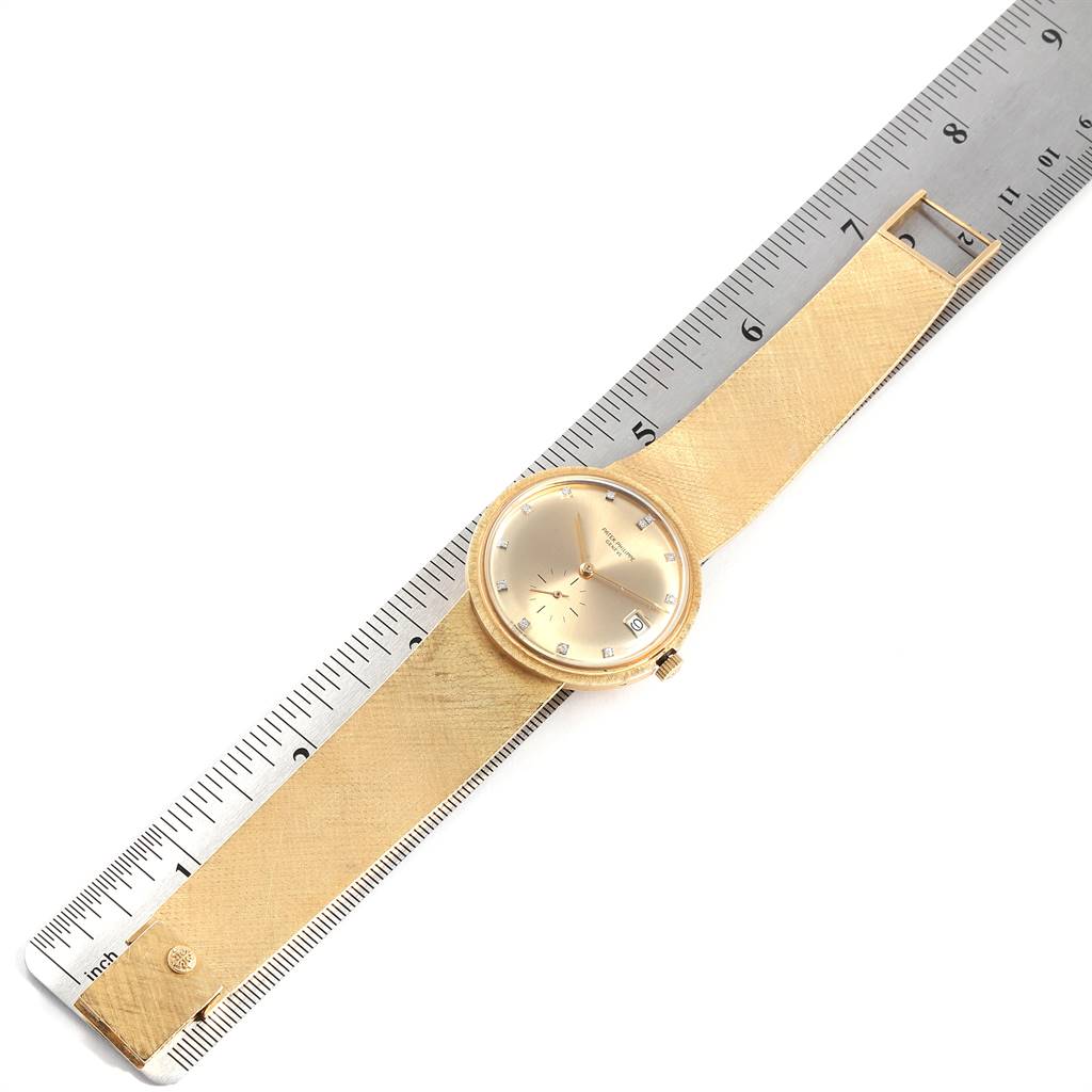 The image shows a vintage Patek Philippe watch laid flat with a ruler for scale, featuring its dial, strap, and crown.