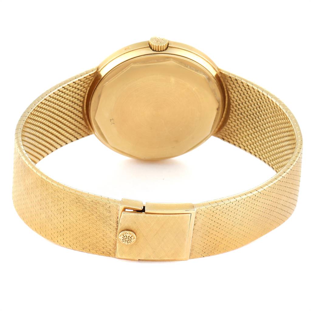 The image shows the back of a Vintage Patek Philippe watch, highlighting its gold case and mesh bracelet.