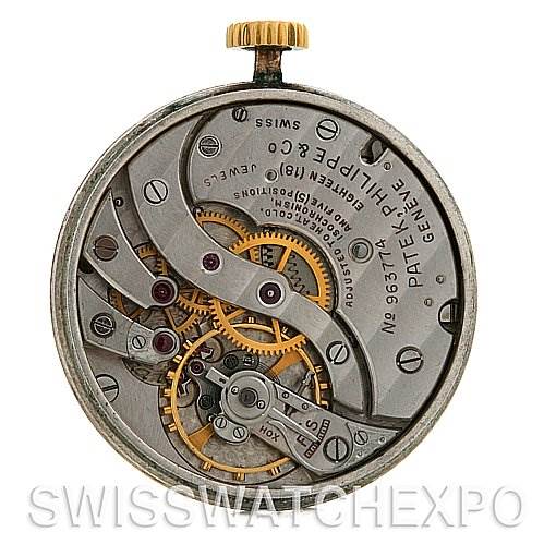 The image shows the inner mechanism of a Vintage Patek Philippe watch, specifically the intricate gears and movements from a rear angle.