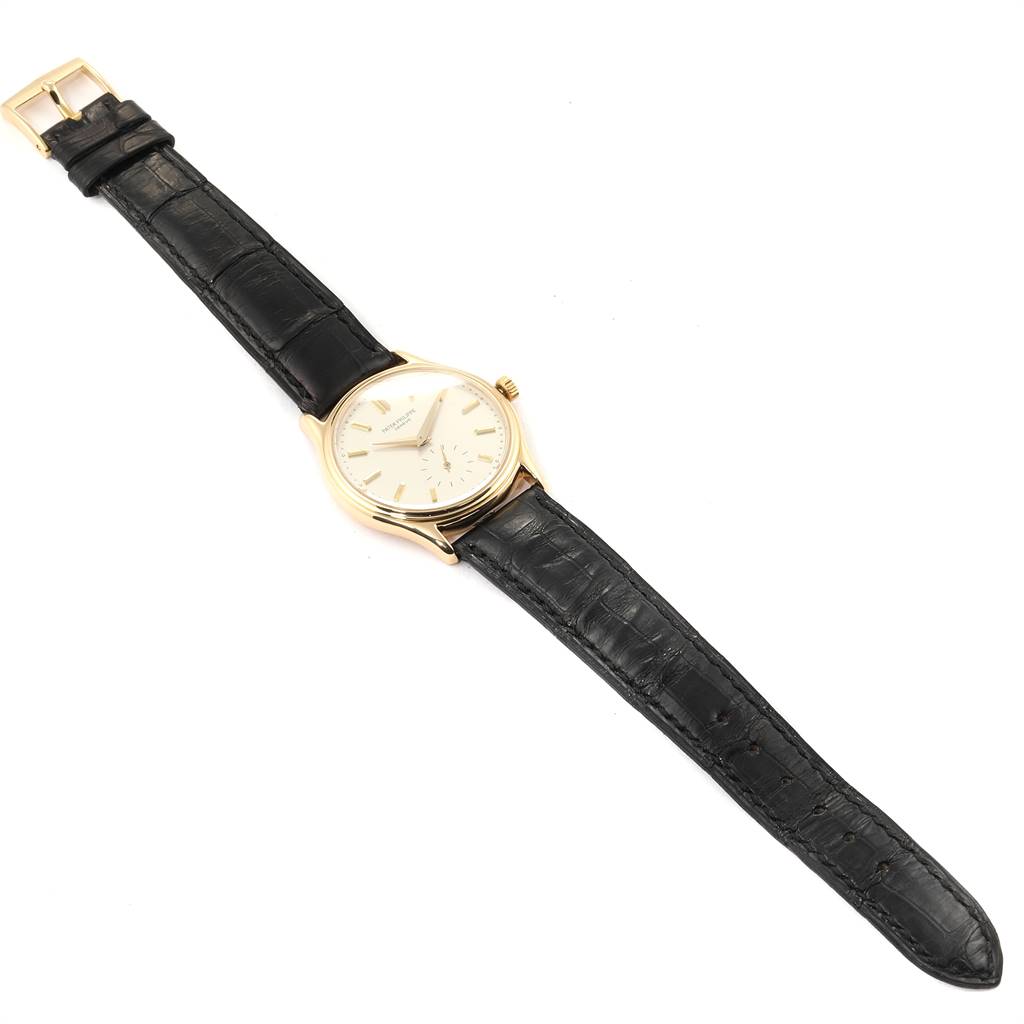The image shows a Calatrava model by Patek Philippe at an angled top view, featuring the watch face, crown, lugs, and leather strap.