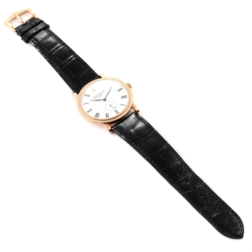 The Patek Philippe Calatrava 5119R Men's Rose Gold White Dial 5119R Men's Rose Gold White Dial watch is shown from a top-down angle, displaying its face, bezel, crown, and black leather strap.