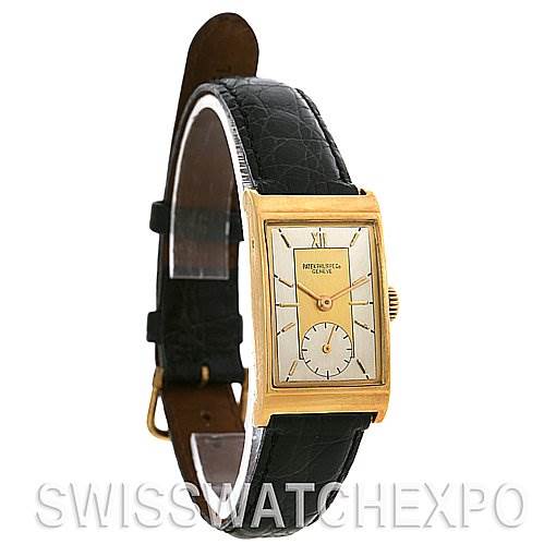 The image shows a side angle of a vintage Patek Philippe watch with a rectangular gold case, black leather strap, and silver dial.