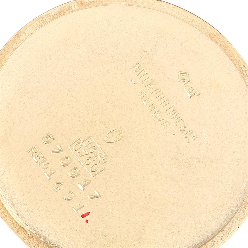 This is a close-up of the case back from a Vintage Patek Philippe watch, showcasing engravings and gold hallmarks.