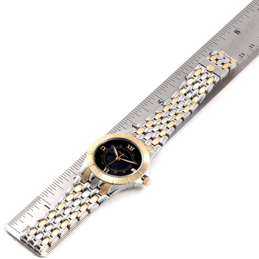 The Patek Philippe Neptune 5080/IJA Men's Steel and Gold (two tone) Black Dial 5080/IJA Men's Steel and Gold (two tone) Black Dial watch is shown laid flat, face up, with its bracelet stretched out next to a ruler for scale.