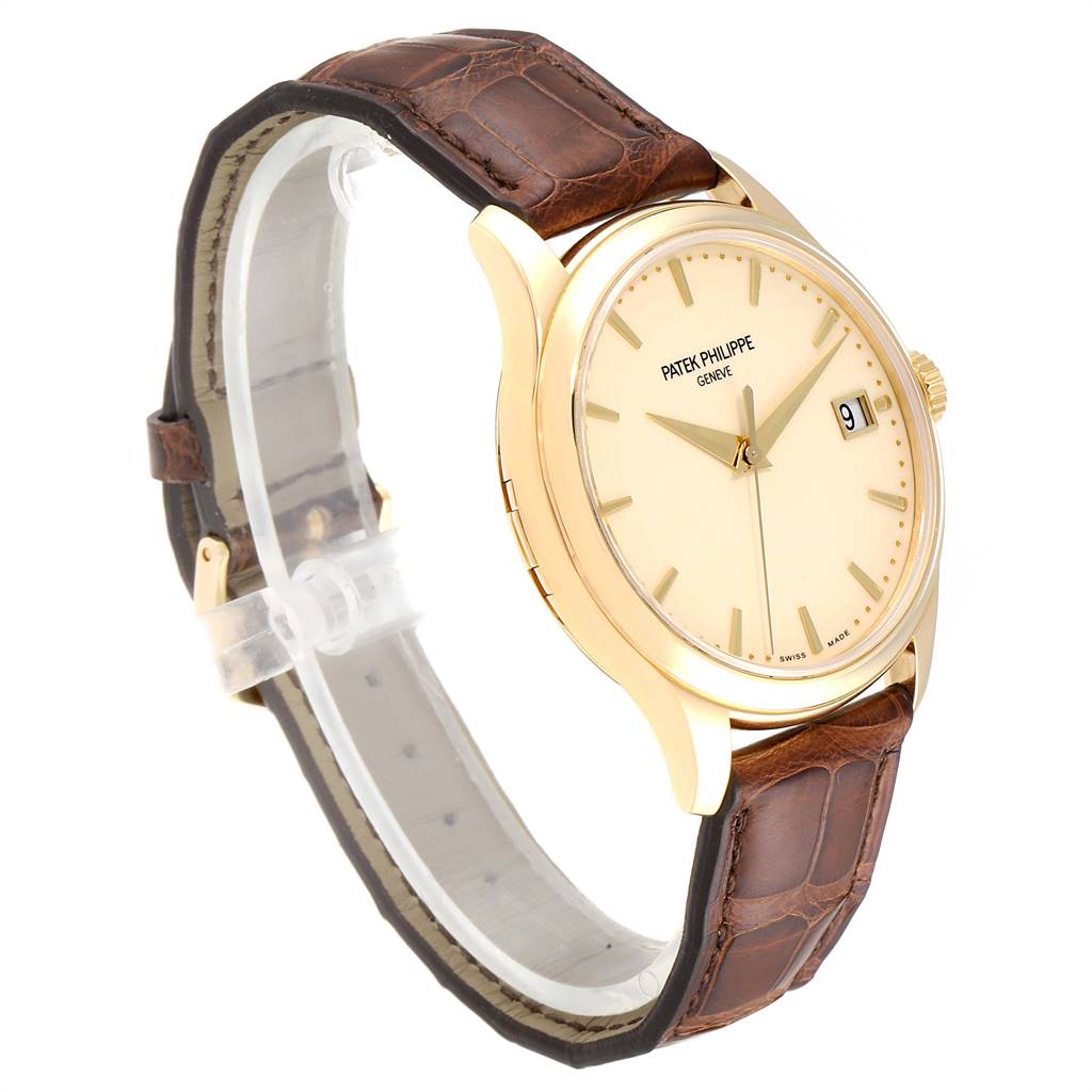 This image shows a Patek Philippe Calatrava 5227 Men's Yellow Gold Beige Dial 5227 Men's Yellow Gold Beige Dial watch at a slight angle, highlighting the face, bezel, and brown leather strap.