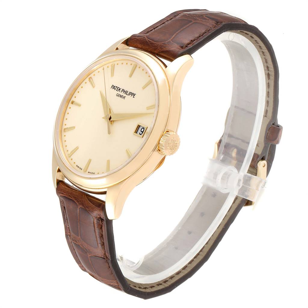 This image shows a Patek Philippe Calatrava 5227 Men's Yellow Gold Beige Dial 5227 Men's Yellow Gold Beige Dial watch at a three-quarter angle, highlighting the dial, crown, and leather strap.