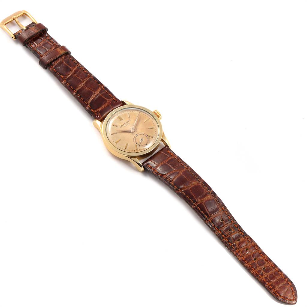 The image shows a top view of a vintage Patek Philippe watch with a brown leather strap and a gold case.