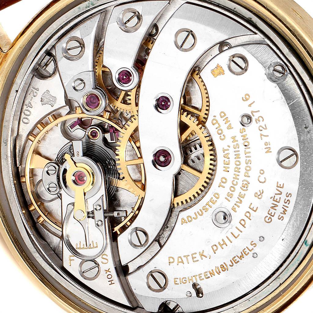 The image shows the intricate inner mechanism of a Vintage Patek Philippe watch, focusing on the gears and balance wheel.