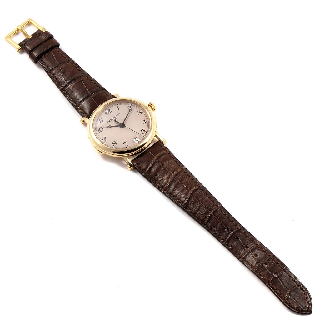 The Patek Philippe Calatrava 5053 Men
s Yellow Gold Beige Dial 5053 Men
s Yellow Gold Beige Dial watch is shown from a top-down view, displaying the face, brown leather strap, and buckle.
