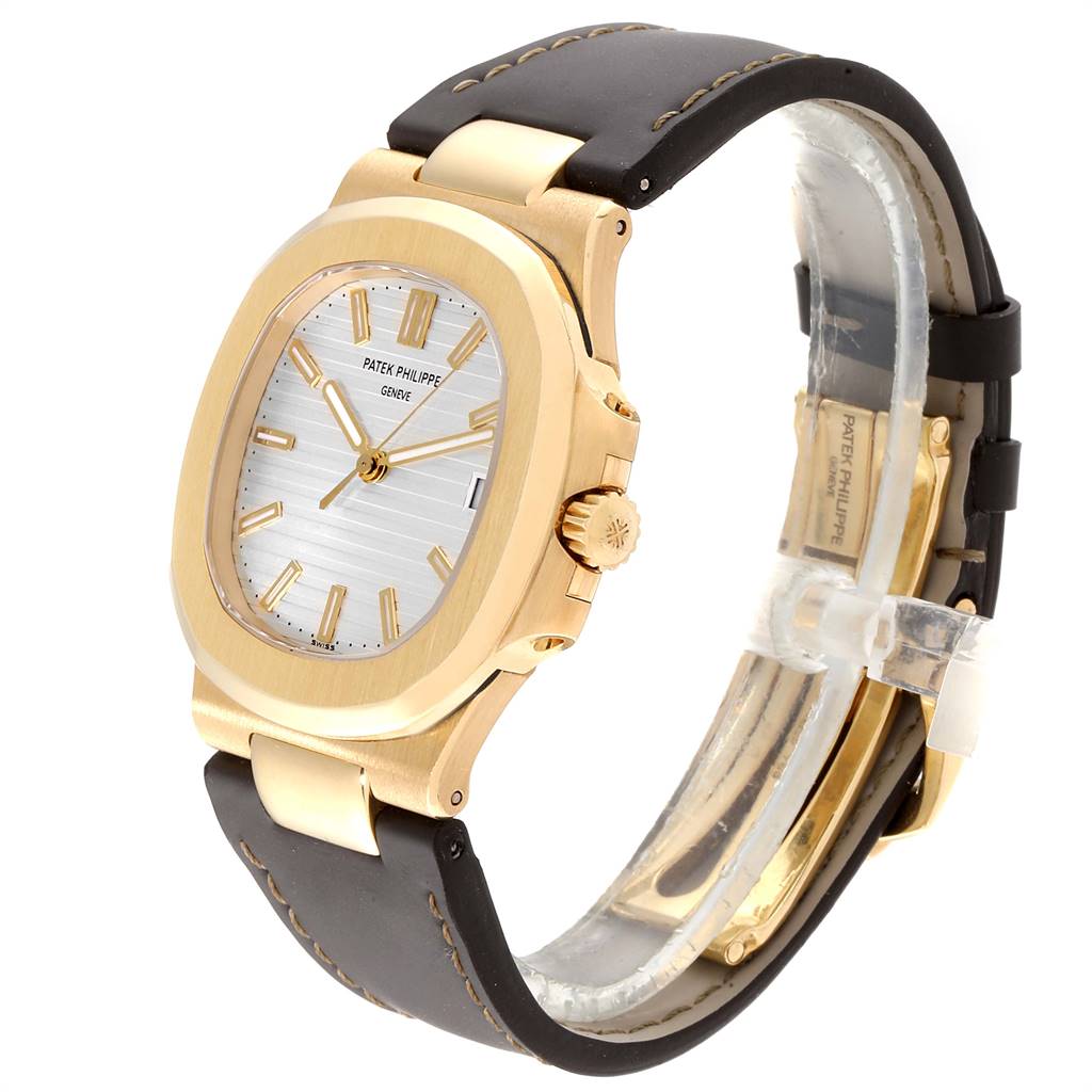 This image shows a Patek Philippe Nautilus 5711J Men's Yellow Gold Silver Dial 5711J Men's Yellow Gold Silver Dial watch from an oblique angle, highlighting the face, bezel, crown, and strap.