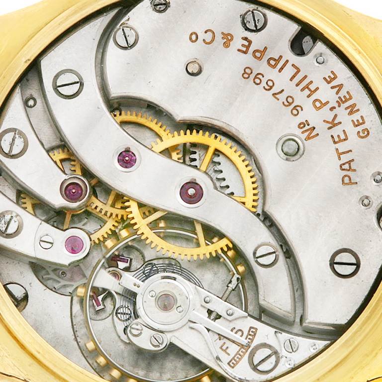 This is a close-up image of the movement mechanism inside a Vintage Patek Philippe watch, showing gears and components.