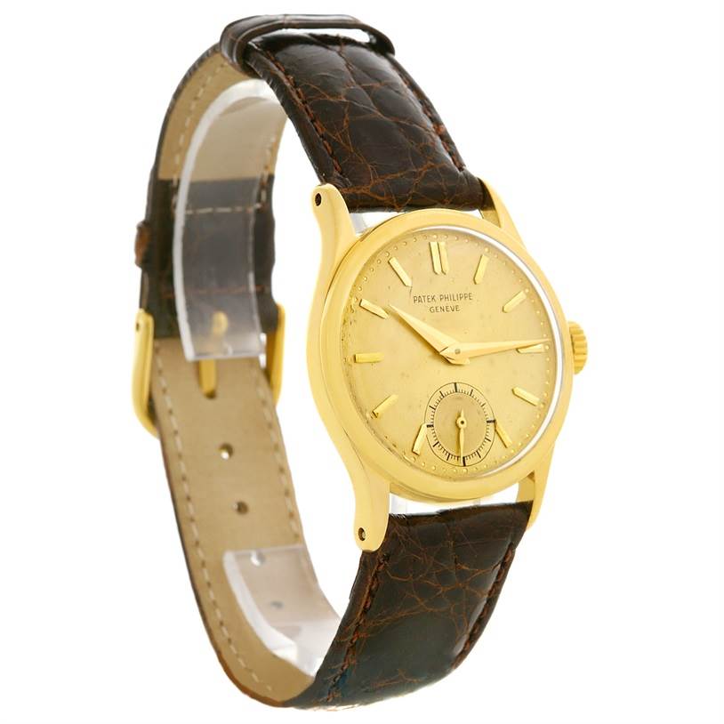 The image shows a Vintage Patek Philippe watch at an angled side view, highlighting its gold case, face, and dark leather strap.
