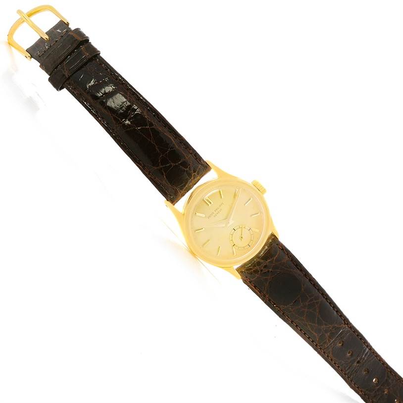 The image shows a top-down view of a Vintage Patek Philippe watch with a brown leather strap and a gold case.