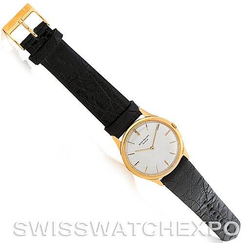 The image shows a top view of a Vintage Patek Philippe watch with a black leather strap and gold case.