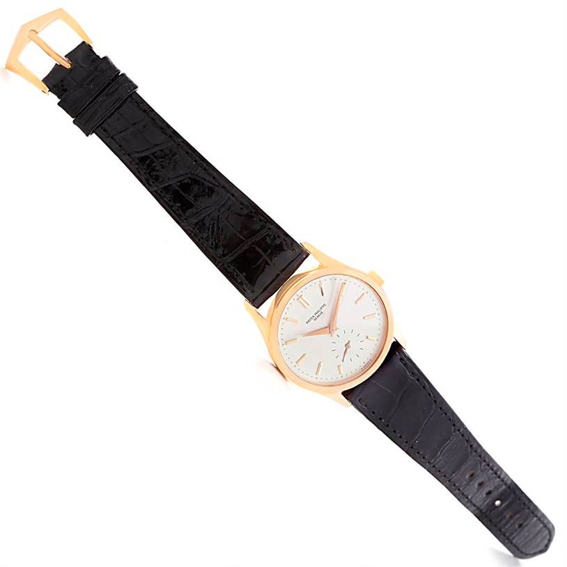 The image shows a top-down view of a Vintage Patek Philippe watch featuring a black leather strap and a gold case with a white dial.