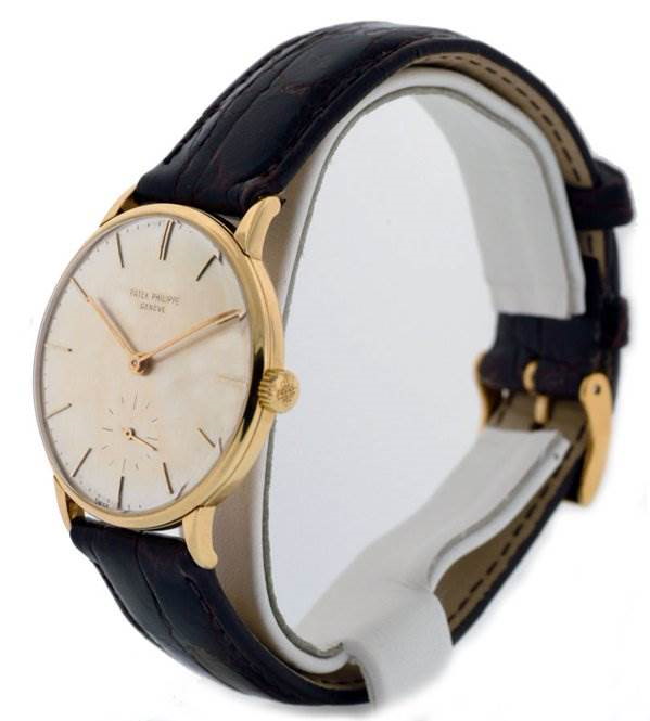 This image shows a side angle view of a Vintage Patek Philippe watch, highlighting its gold case, dial, and leather strap.