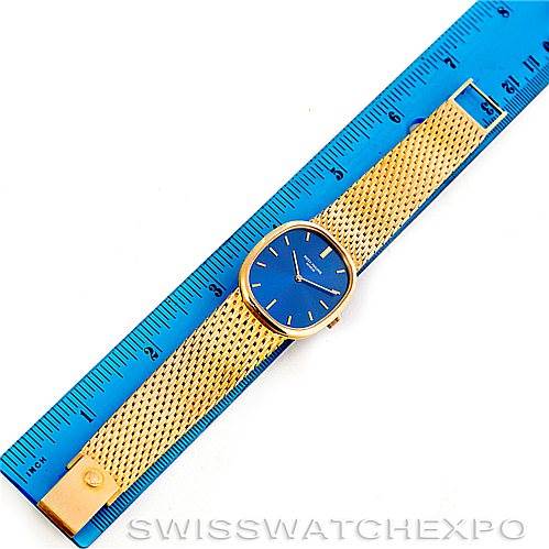 The image shows a Patek Philippe Golden Ellipse 3548/1 Men's Yellow Gold Blue Dial 3548/1 Men's Yellow Gold Blue Dial watch laid flat next to a blue ruler, displaying the watch face and golden mesh strap.