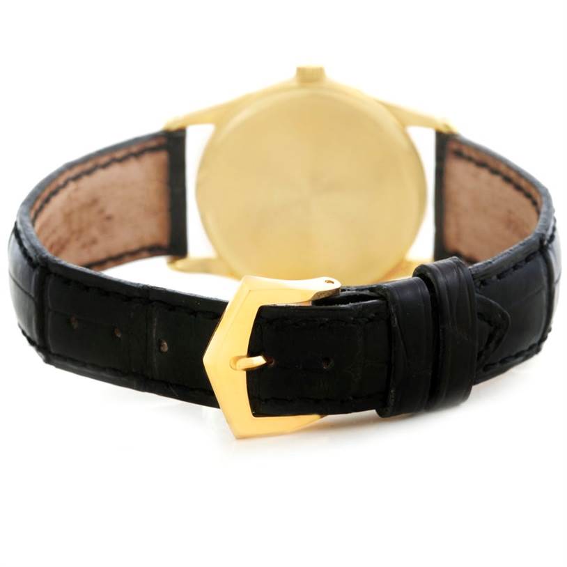 This image shows the back view of a Patek Philippe Calatrava 3796 Men's Yellow Gold Silver Dial 3796 Men's Yellow Gold Silver Dial watch, including its gold case, black leather strap, and gold buckle.