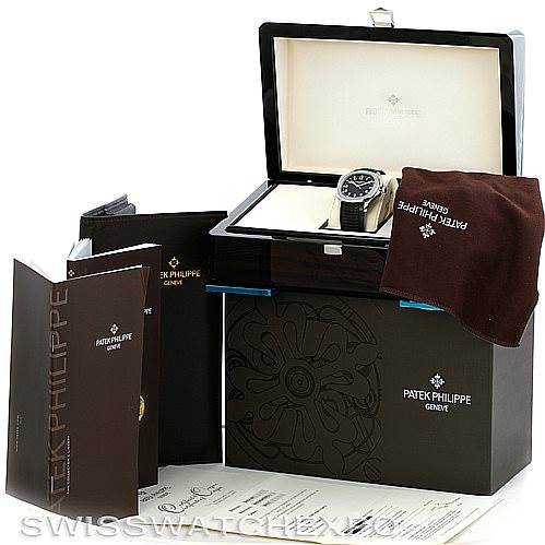 The image shows a Patek Philippe Aquanaut 5167A Men's Stainless Steel Black Dial 5167A Men's Stainless Steel Black Dial watch in its open box, with accompanying booklets, a cloth, and papers.