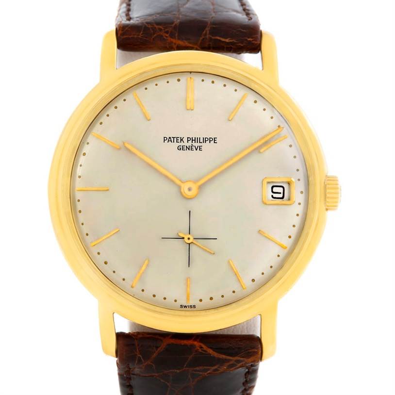 The image shows a front view of a vintage Patek Philippe watch with a gold case, white dial, and brown leather strap.