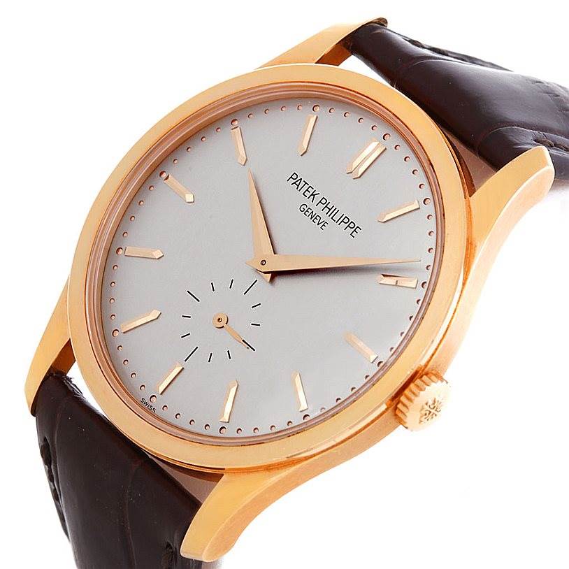 A Patek Philippe Calatrava 5196R Men's Rose Gold Silver Dial 5196R Men's Rose Gold Silver Dial watch is shown at an angle that highlights the dial, watch crown, and part of the leather strap.
