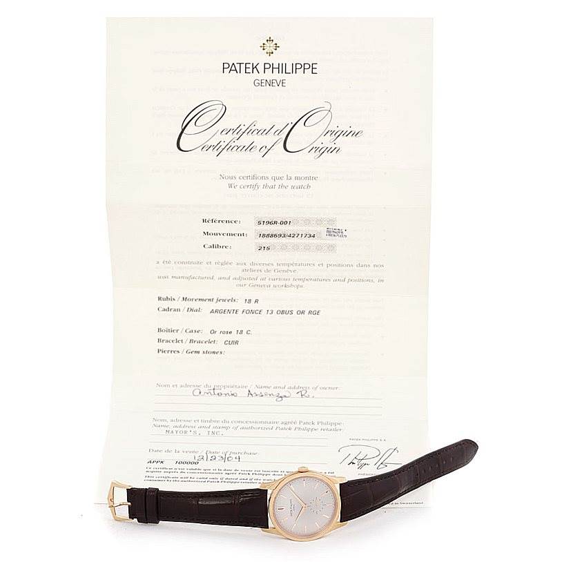 The image shows a Patek Philippe Calatrava 5196R Men's Rose Gold Silver Dial 5196R Men's Rose Gold Silver Dial watch displayed at a slight angle, with its certificate of origin in the background.