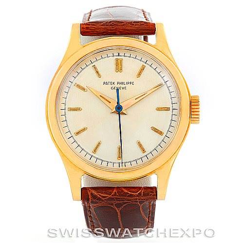 The image shows a frontal view of a Vintage Patek Philippe watch with a gold case, white dial, brown leather strap, and gold hour markers.