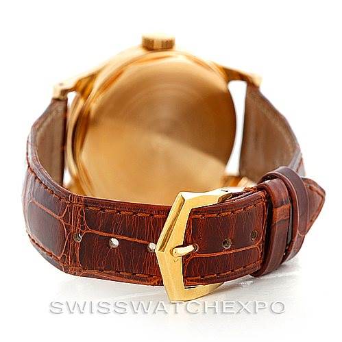 This image shows the back view of a vintage Patek Philippe watch, highlighting the gold case and brown leather strap with a gold buckle.