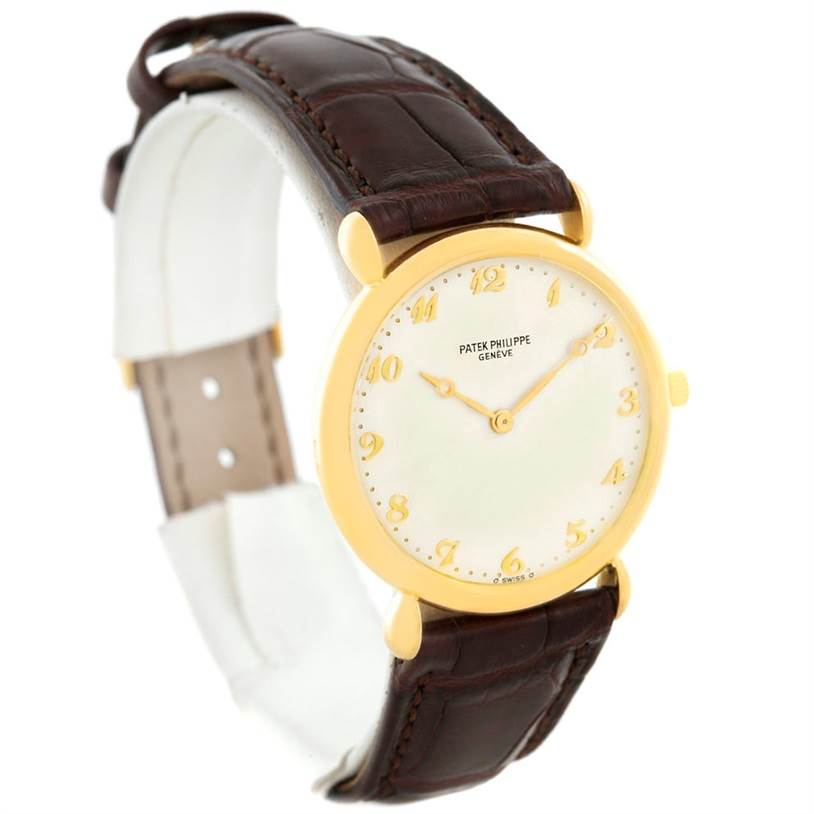 This image shows a side view of a Vintage Patek Philippe watch, highlighting its gold case, white dial, and brown leather strap.