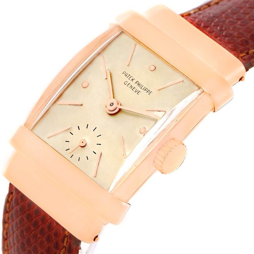 The vintage Patek Philippe watch is shown at an angle revealing its face, crown, and leather strap.