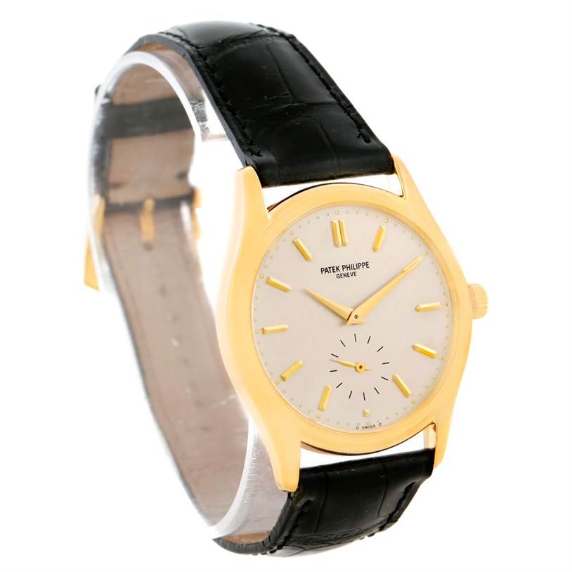 The Patek Philippe Calatrava 5023 Men's Yellow Gold Silver Dial 5023 Men's Yellow Gold Silver Dial watch is shown at a three-quarter angle, highlighting its face, black leather strap, and golden casing.