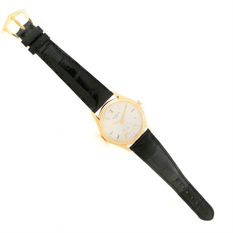 The image shows a Patek Philippe Calatrava 5023 Men's Yellow Gold Silver Dial 5023 Men's Yellow Gold Silver Dial watch with a black leather strap, viewed from a top-down angle.