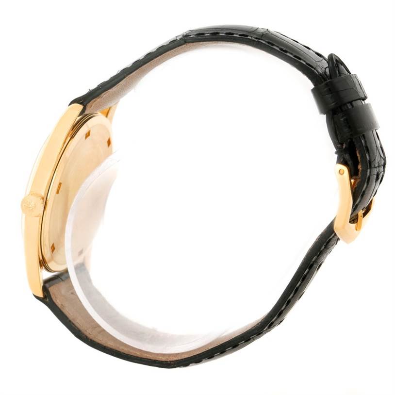 The image shows a side view of a Patek Philippe Calatrava 5023 Men's Yellow Gold Silver Dial 5023 Men's Yellow Gold Silver Dial watch highlighting its gold case, black leather strap, and buckle.